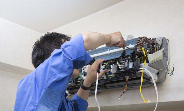 HVAC technician repairing an outdoor air conditioner in St. Louis, MO