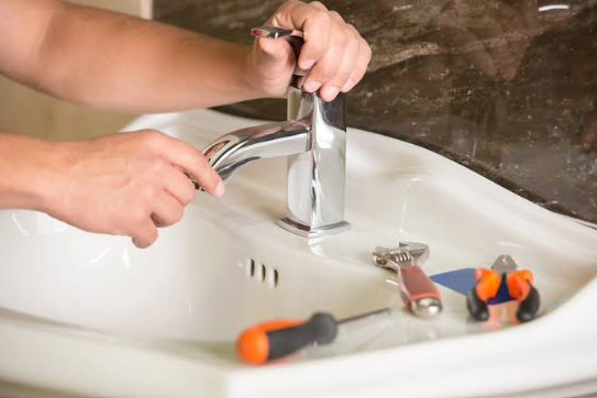 Professional plumber repairing a modern kitchen faucet in St. Louis, MO